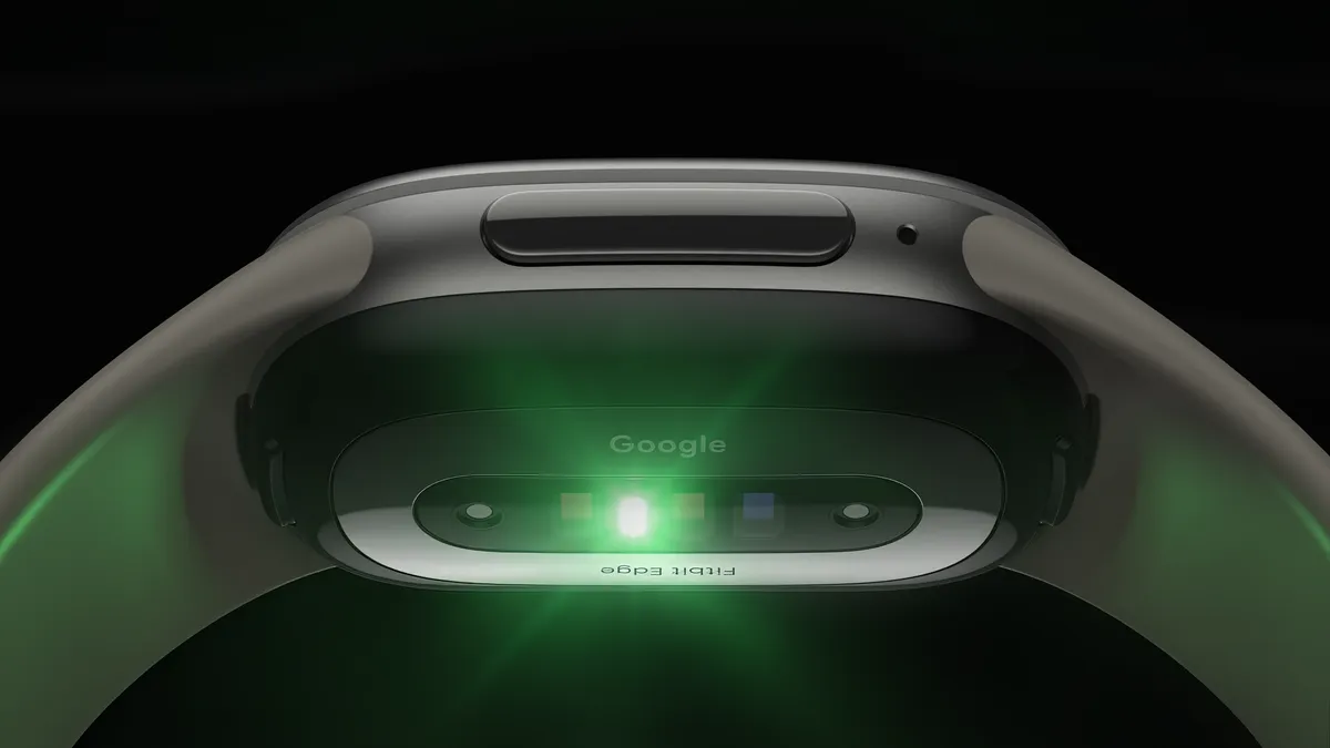 Underside of the Fitbit Edge, showing its health-sensor array lit up green