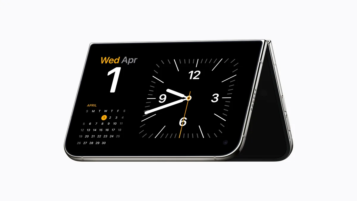 iPhone Duo partly folded and standing on its side in StandBy, showing a large clock face, the date and a mini calendar